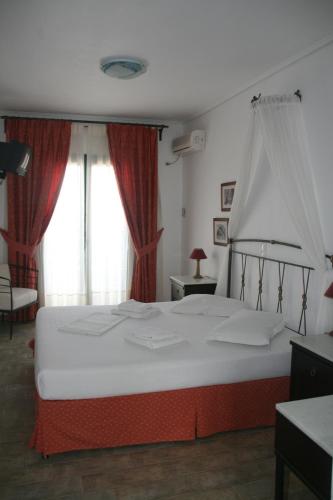 a bedroom with a large bed with red curtains at Dionysos Hotel in Skala