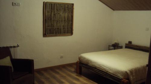 a bedroom with a bed and a chair and a window at Quinta dos Gata in Nabainhos