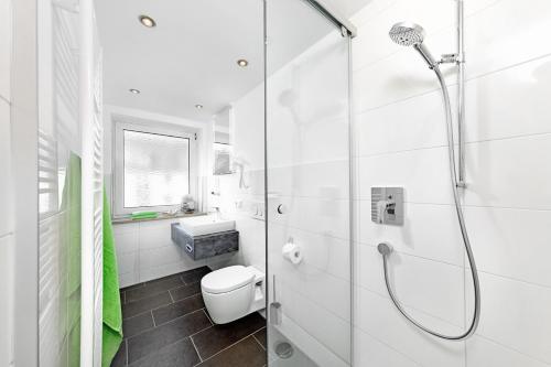 a white bathroom with a shower and a toilet at Hotel Gasthaus zum Zecher in Lindau