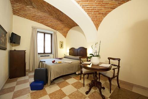 a bedroom with a bed and a table in a room at Albergo La Corte Albertina in Bra