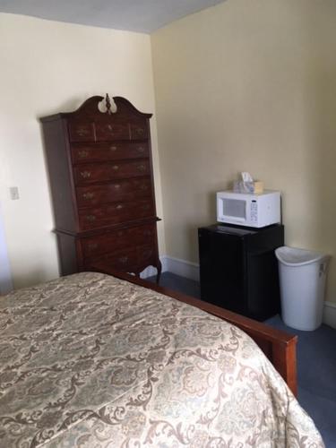 a bedroom with a bed and a dresser and a microwave at Victorian Charm Inn in Towanda
