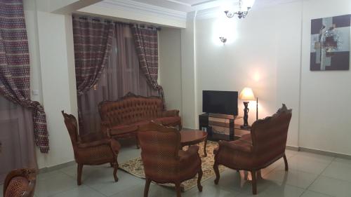 sala de estar con sillas, mesa y TV en Résidence hôtelière La Roseline, en Yaoundé