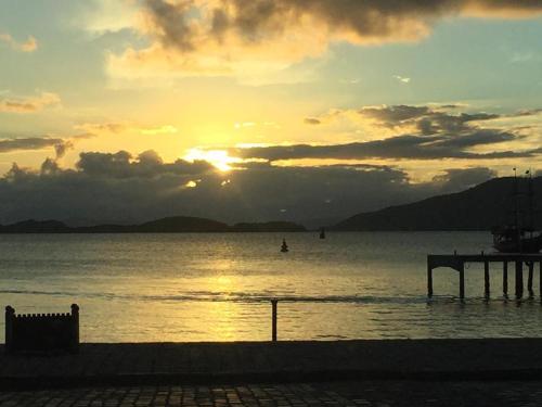 a sunset over a body of water with a pier at Hotel Zibamba in São Francisco do Sul
