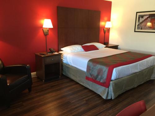 a hotel room with a large bed and a chair at Ramada by Wyndham Torrance in Torrance