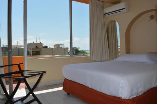 - un lit et une chaise dans une chambre avec fenêtre dans l'établissement Hotel del Parque, à Ciudad del Carmen