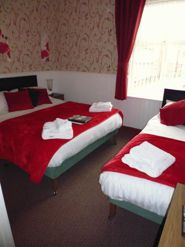 two beds in a hotel room with red and white towels at Kingscliff in Blackpool