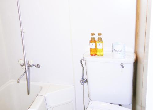 a bathroom with a toilet and two bottles of alcohol at FLEXSTAY INN Sugamo in Tokyo