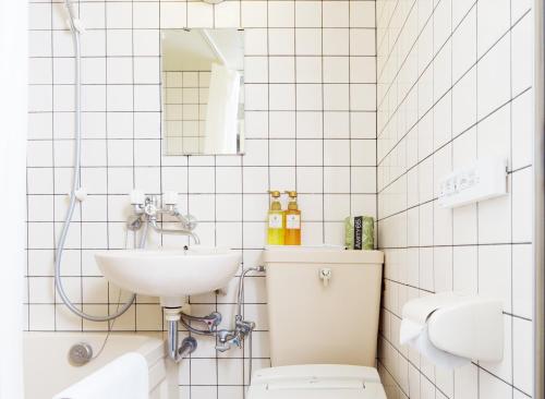 a white tiled bathroom with a sink and a toilet at FLEXSTAY INN Shirogane in Tokyo