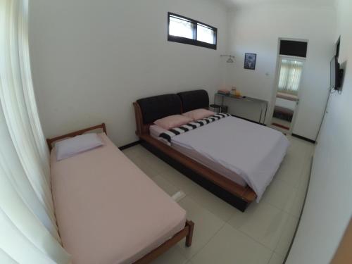 a bedroom with two beds and a window at Mess Inn Semarang in Semarang