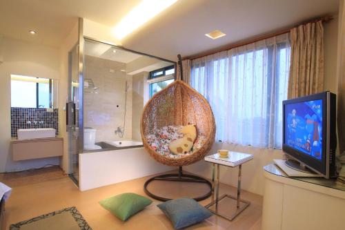 a bathroom with a television and a wicker chair in a room at Ying Yue Villa in Datong