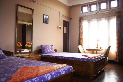 een slaapkamer met 2 bedden, een tafel en een raam bij Eagle Nest Home Stay in Guwahati