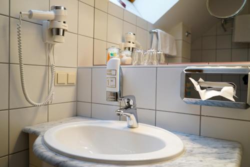 La salle de bains est pourvue d'un lavabo blanc et d'un miroir. dans l'établissement Pension Besser, à Eisenkappel-Vellach