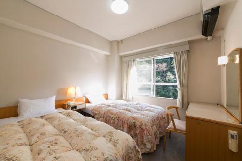 una camera d'albergo con due letti e una finestra di Sansuikan Kawayu Matsuya a Hongu