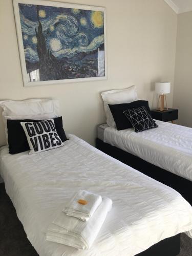 a bedroom with two beds and a painting on the wall at Rosewhite House in Myrtleford