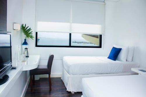 a hotel room with two beds and a desk and a television at Ellis Ecotel in Legazpi