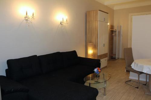 - un salon avec un canapé noir et une table dans l'établissement Stars Berlin Apartments Essener Straße, à Berlin