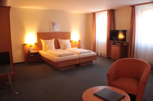 a hotel room with a bed and a tv at Hotel Blauer Wolf in Gunzenhausen