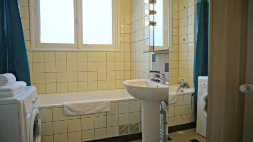 La salle de bains est pourvue d'un lavabo, d'une baignoire et d'une fenêtre. dans l'établissement Little Suite - Marceau, à Lille