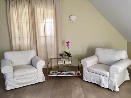 two white chairs and a table in a living room at Liszkay Borkúria in Monoszló
