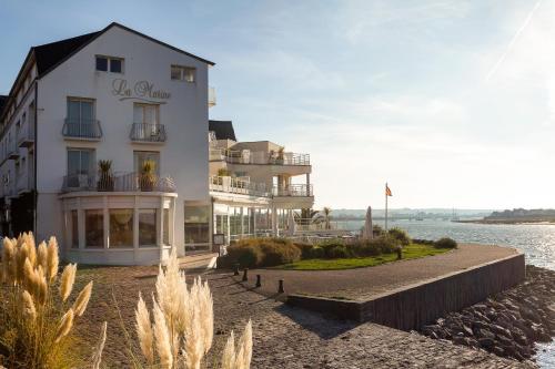 a large white building next to a body of water at Hôtel La Marine in Barneville-Carteret