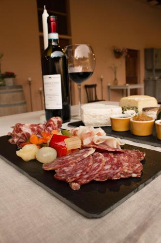 a plate of meat and cheese and a bottle of wine at Agriturismo Cascina Magana in Burago di Molgora