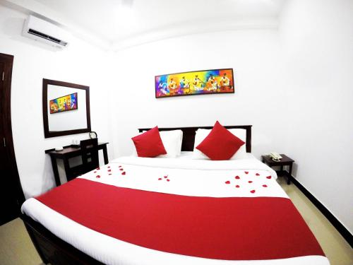 a bedroom with a red and white bed with red pillows at Colombo Residency in Colombo