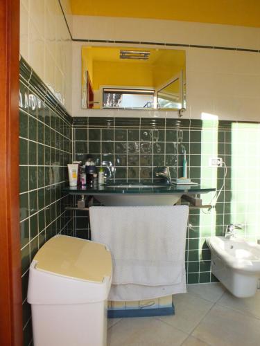 a green tiled bathroom with a toilet and a sink at Villa Etrusca in Marina di Campo