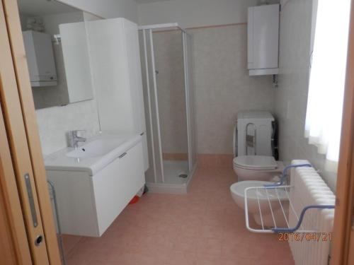 een badkamer met een wastafel, een toilet en een douche bij Appartamenti Presanella in Vermiglio