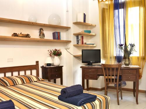 a bedroom with a bed and a desk with a television at Domo Silvia E Paolo in Nuoro