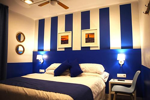 a blue and white bedroom with a bed and a chair at Hostal Miranda in Blanes