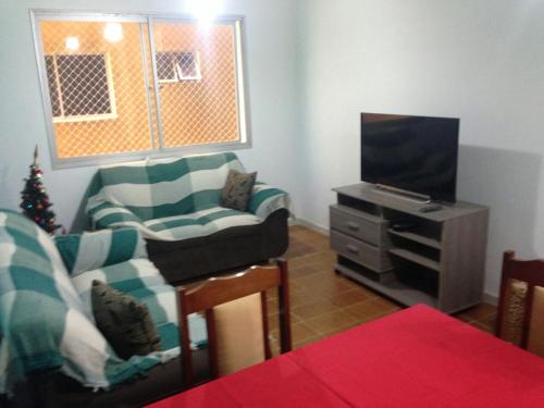ein Wohnzimmer mit einem Sofa und einem TV in der Unterkunft Apartamento frente ao mar Florida Praia Grande in Praia Grande