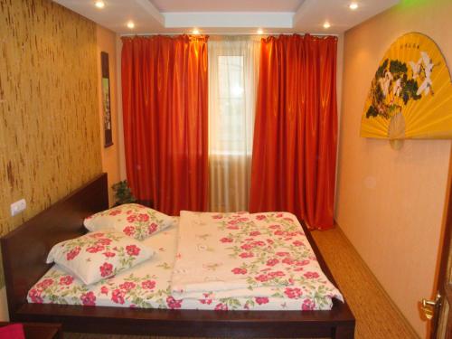 ヘルソンにあるMaxim Apartmentのベッドルーム1室(赤いカーテンと窓付きのベッド1台付)