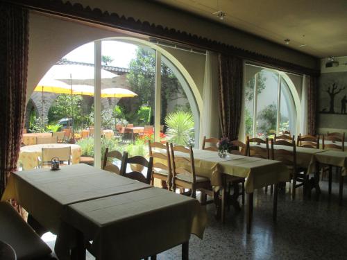 a dining room with tables and chairs and large windows at Hotel Arcadia in Ascona