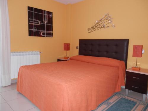 a bedroom with a bed with an orange bedspread at Apartamentos Monte Hernanz in Riaza