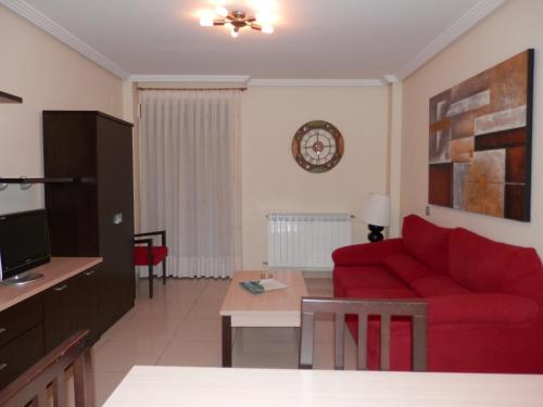 a living room with a red couch and a table at Apartamentos Monte Hernanz in Riaza