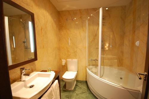 Hotel Los Usías في Dos Torres: حمام مع حوض وحوض استحمام ومرحاض