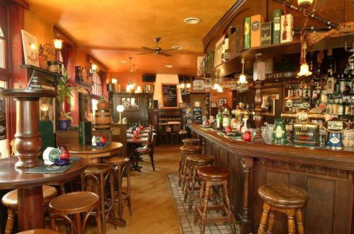 a bar with tables and stools in a room at The Pipers in Middelkerke