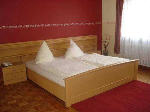 a bed with white sheets and pillows in a room at Traditionsgasthof Zum Luedertal in Bimbach