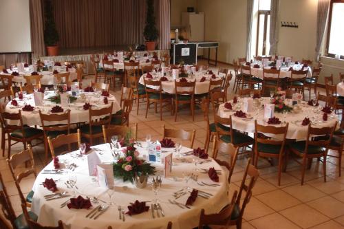 uma sala cheia de mesas e cadeiras com toalhas de mesa brancas em Traditionsgasthof Zum Luedertal em Bimbach