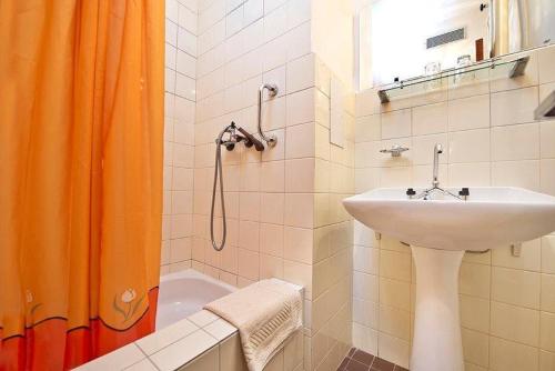 bagno con tenda arancione e lavandino di Hotel SOREA MARMOT a Demänovská Dolina