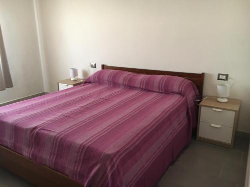 1 dormitorio con 1 cama de color púrpura y 2 mesitas de noche en Appartamento Cavalieri, en Santa Maria Navarrese