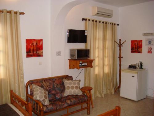 ein Wohnzimmer mit einem Sofa und einem TV in der Unterkunft Boussetil Rooms CapAnMat in Tinos