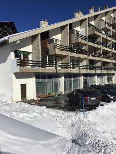 a building with cars parked in a parking lot in the snow at Appartement Noécie in Les Crosets