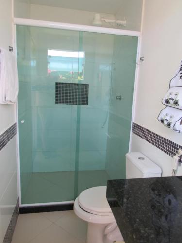 a bathroom with a glass shower with a toilet at Pousada Mangas in Manguinhos