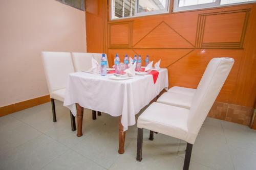 einen weißen Tisch mit weißen Stühlen und Flaschen darauf in der Unterkunft Sunshine Hotel Tengecha in Kericho