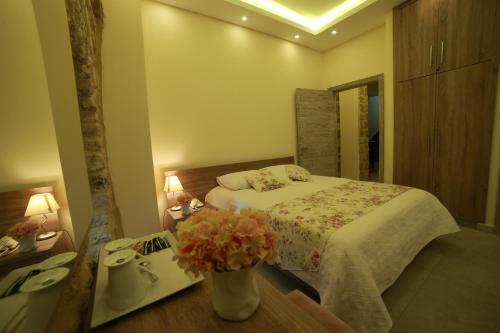a bedroom with a bed and a table with flowers at Asamina Boutique Hotel in Soûr