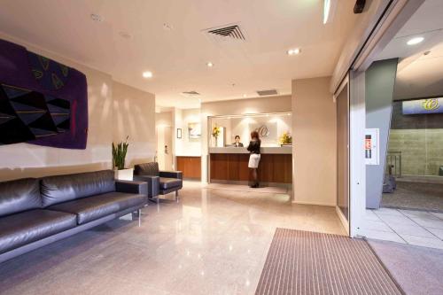 a lobby with a couch and a person in a counter at VR Auckland City in Auckland