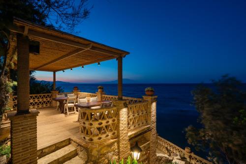 una terrazza in legno con tavolo e sedie sull'oceano di Porta del mar Beach Resort a Méson Yerakaríon