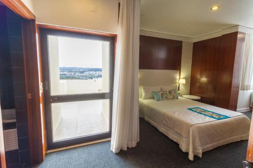 a bedroom with a bed and a large window at Hotel Eurosol Leiria & Jardim in Leiria