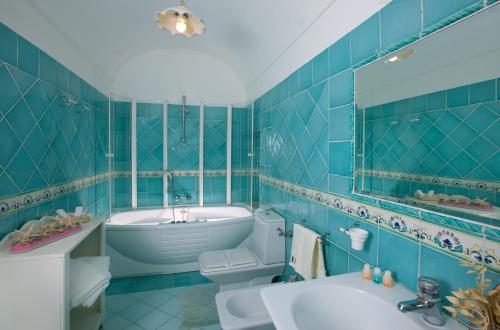 baño de azulejos azules con bañera y lavamanos en B&B Il Tramonto, en Anacapri